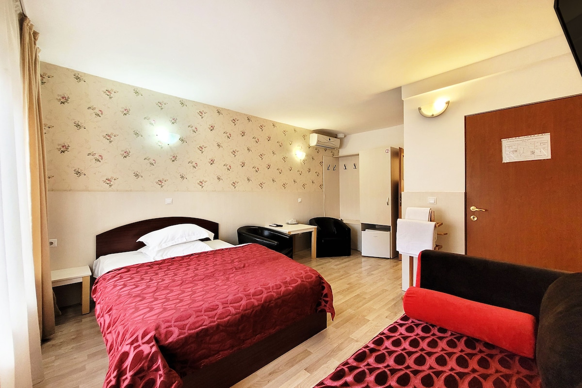 Une chambre d’hôtel comprenant un lit, un bureau, une armoire et un petit coin salon.