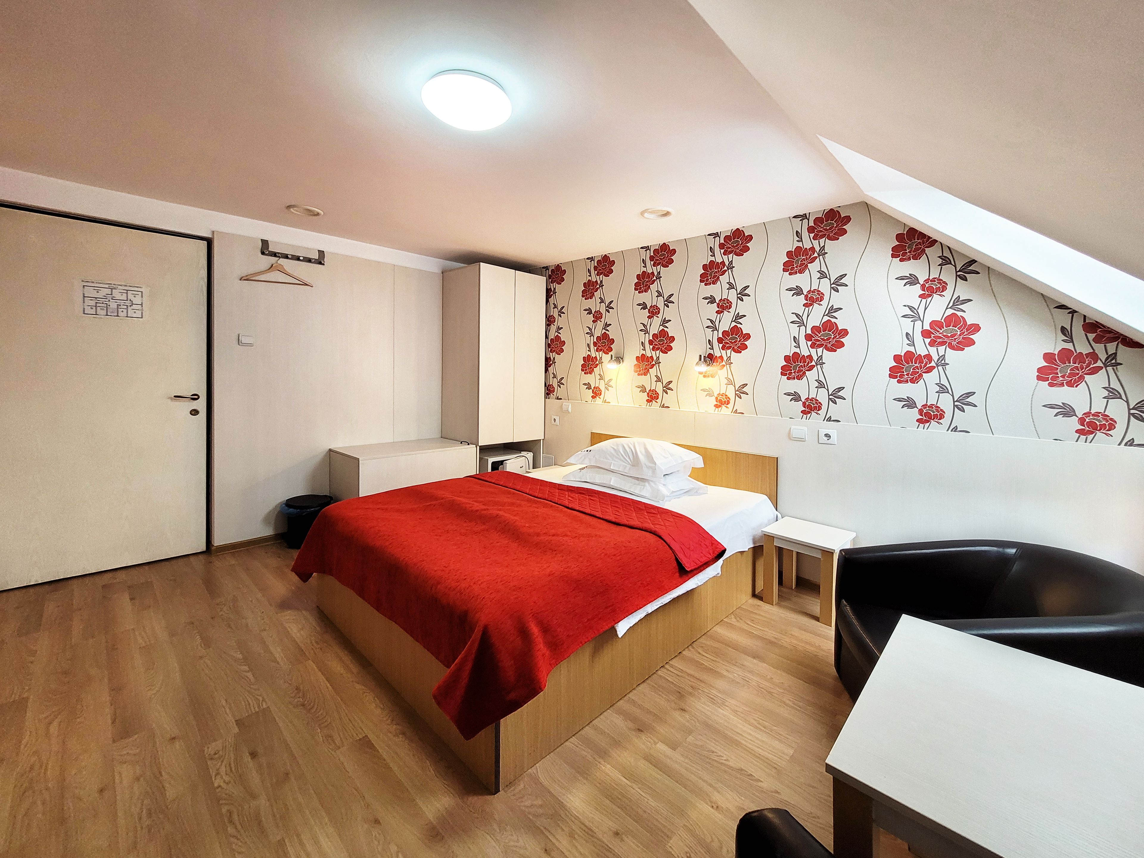 Una habitación de hotel con cama, mesita de noche, silla y armario.
