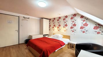 Una habitación de hotel con cama, mesita de noche, silla y armario.