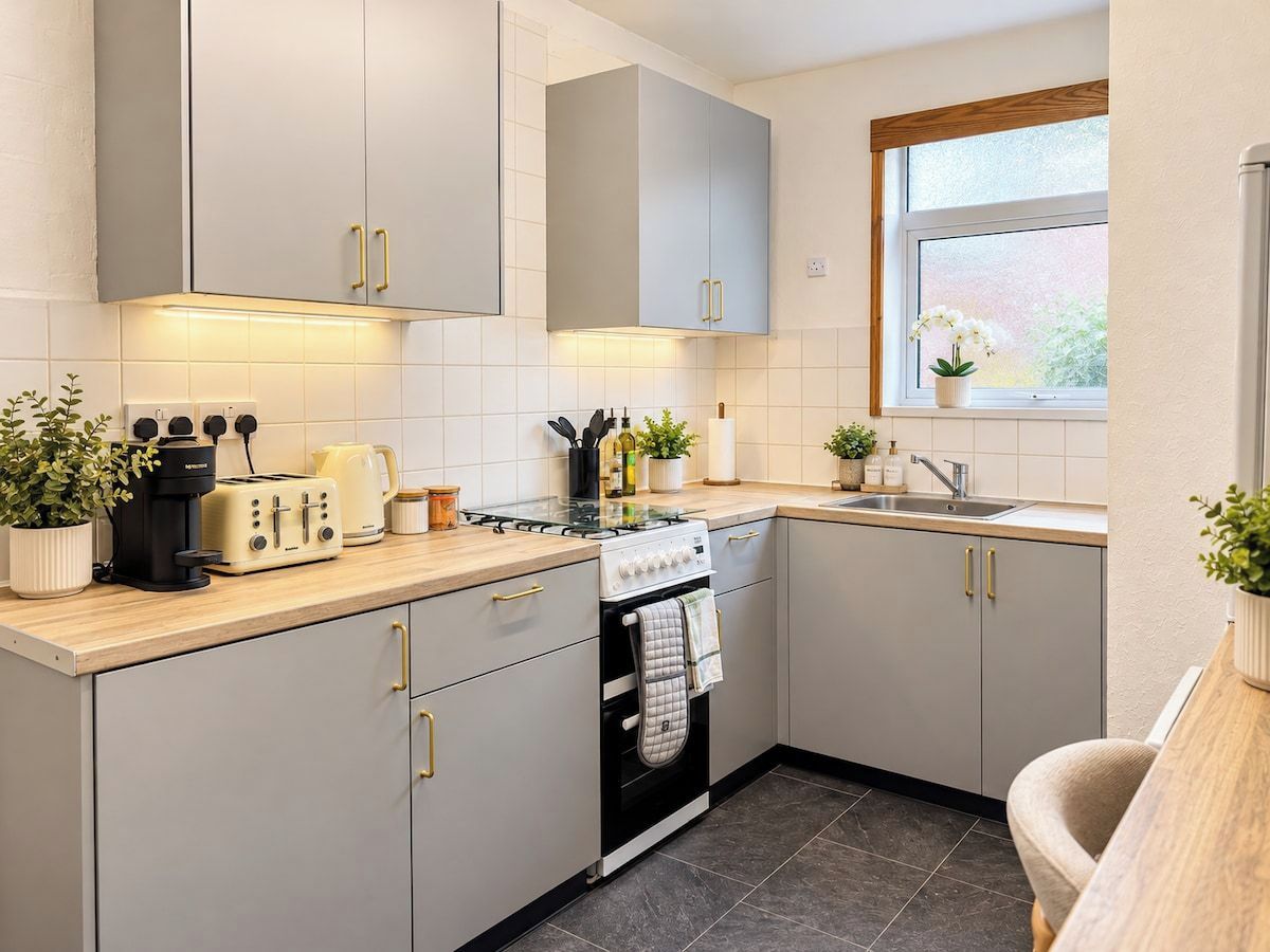 Une cuisine moderne avec des meubles gris, une cuisinière, un évier et une fenêtre donnant sur un beau paysage.