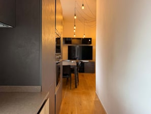 Cozinha moderna com armário cinza escuro, piso de madeira e área de jantar com mesa e cadeiras.