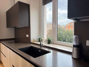 A modern kitchen with a large window, a built-in sink, and a coffee maker on the counter. - Terrazza Gramsci – Spacious Private Terrace (Bologna)