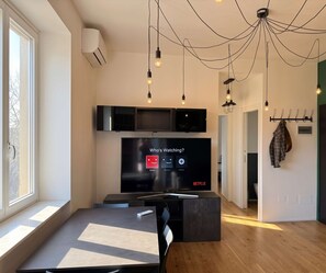 A modern living room with a flat-screen TV displaying a Netflix interface, a fireplace, and a dining area with a table and chairs. - Terrazza Gramsci – Spacious Private Terrace (Bologna)
