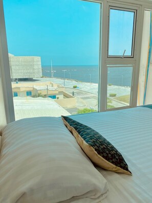 Un lit avec un oreiller et une vue sur la mer par la fenêtre.
