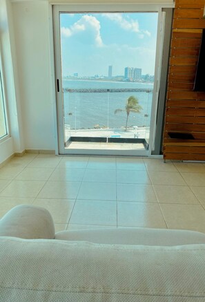 Ein Zimmer mit einer großen Schiebeglas Tür, die auf einen Balkon mit Meer- und Stadtblick führt.