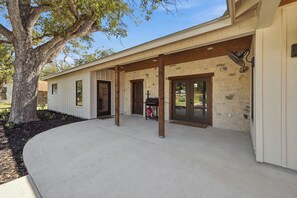 A covered outdoor area with a concrete floor, wooden pillars, and a stone wall. - Iltis Hus on Lisbon | Historic 1853 Limestone Home (Castroville)