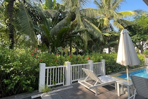 A poolside area with a white fence, lounge chairs, and an umbrella. - Elegant Pool Villa My Khe Beach Danang (Da Nang Municipality)