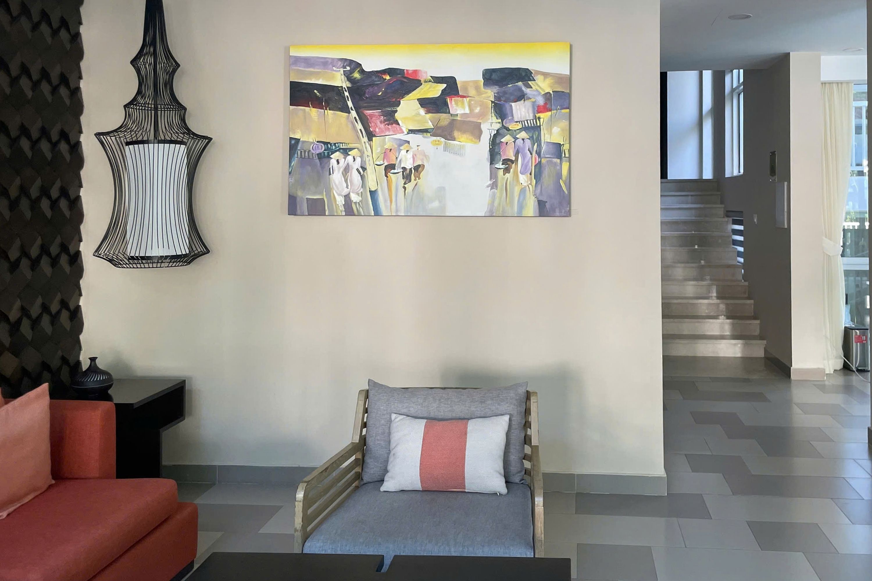 A modern living room with a sofa, a decorative wall hanging, and a staircase leading to another level.