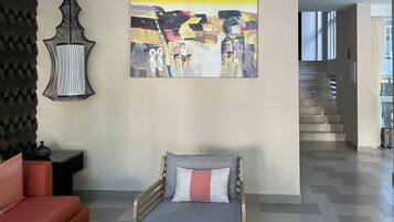 A modern living room with a sofa, a decorative wall hanging, and a staircase leading to another level.