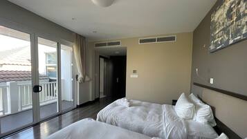 Habitación de hotel con dos camas, un balcón y vistas al exterior.