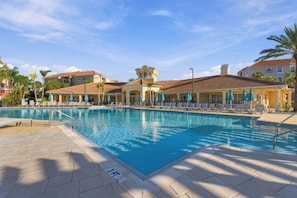 A swimming pool with lounge chairs and umbrellas, surrounded by buildings with a Mediterranean architectural style. - Your Orlando Home with Comfort and Convenience (Orlando)