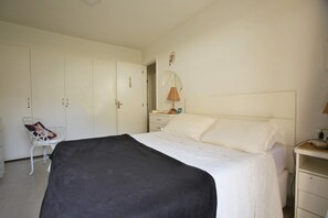 A bedroom with a bed, a chair, a wardrobe, a bedside table, and a mirror. - Casa Alto Astral em Buzios com Piscina (Búzios)