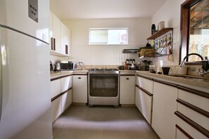 Eine kleine Küche mit weißen Schränken, einem eingebauten Backofen, einer Mikrowelle und einem Fenster über der Spüle.