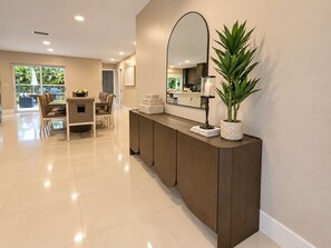A modern interior with a wooden console table, a large mirror, and a potted plant. - The Quiet Luxury (Hollywood)
