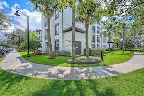 A multi-story residential building with a landscaped front yard, including trees and shrubs. - Amazing Location, 3BR with Comfort and Space for 6 (Orlando)