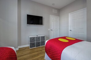 A bedroom with two beds, a television mounted on the wall, and a storage unit with drawers. - Amazing Location, 3BR with Comfort and Space for 6 (Orlando)