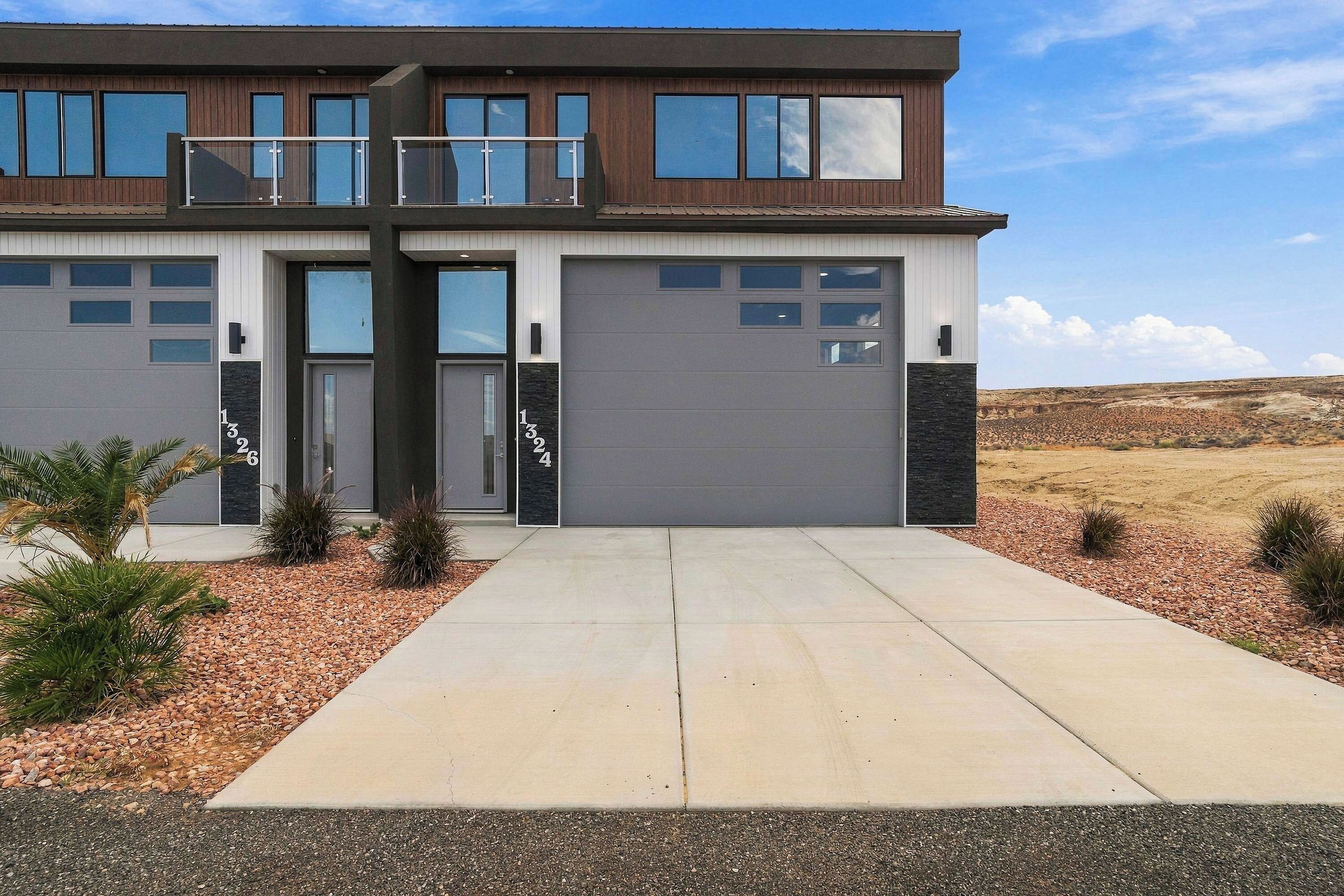 A modern two-story house with a garage, a driveway, and a landscaped front yard.
