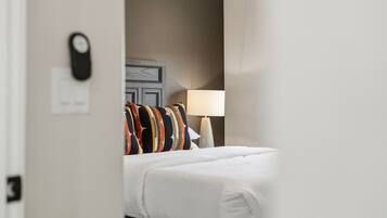 A hotel room with a bed, a nightstand, a lamp, and a wall-mounted clock.