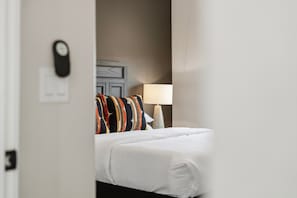 A hotel room with a bed, a nightstand, a lamp, and a wall-mounted clock. - The Desert Terrace- Views, Sleeps 6, 3 BR (Canyon Point)