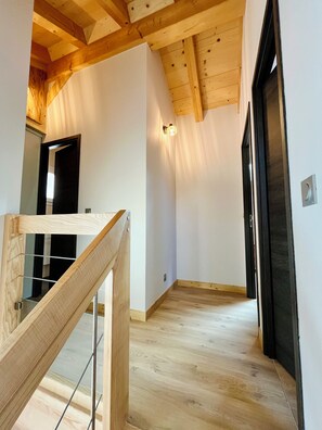 A modern interior with wooden beams, a staircase, and a hallway leading to a door. - New Listing (Brides-les-Bains)