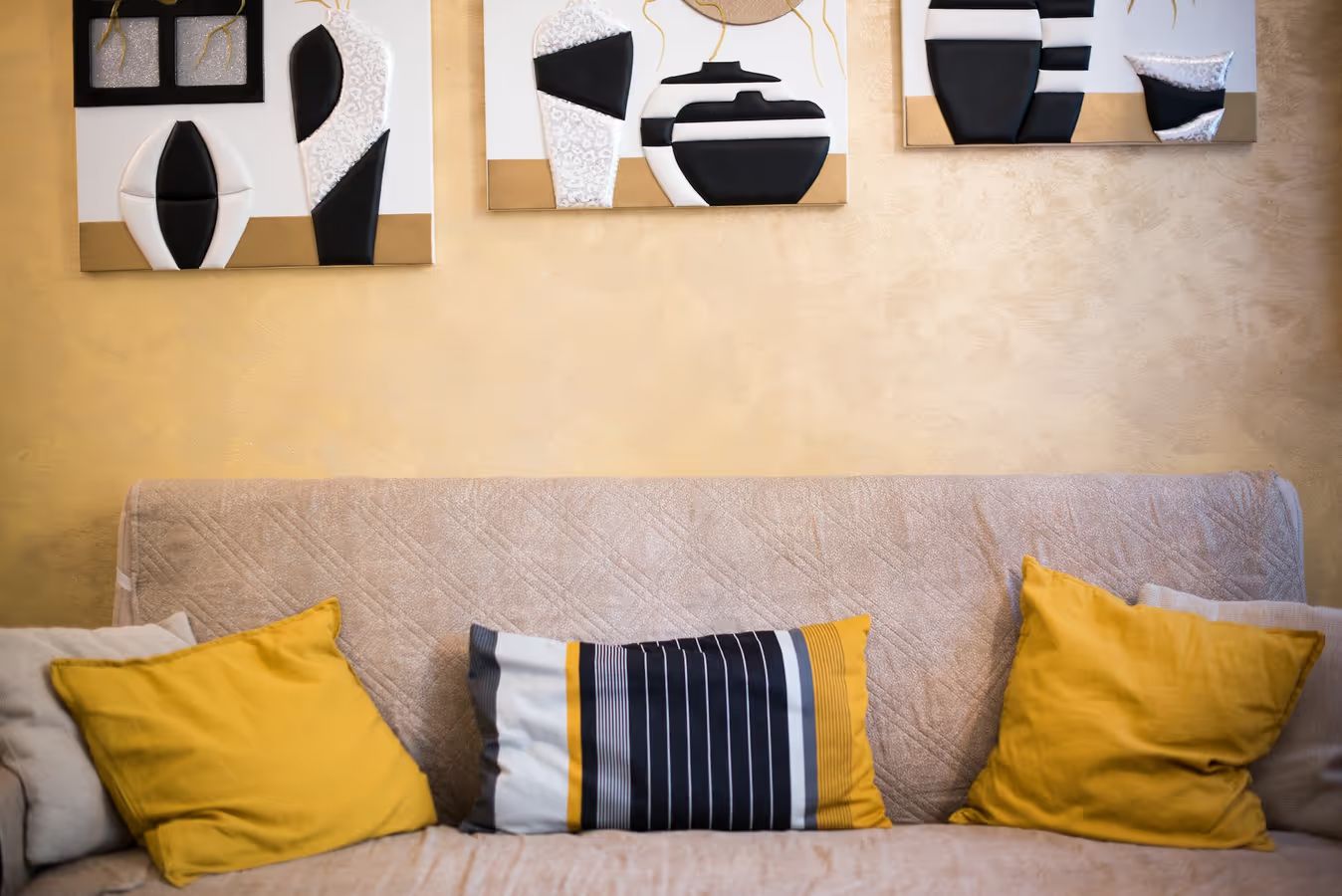 Ein beiges Sofa mit drei Kissen in einem Raum mit strukturierter Wand.