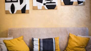 Ein beiges Sofa mit drei Kissen in einem Raum mit strukturierter Wand.