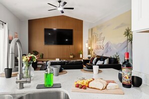 A modern kitchen with a built-in stove, a sink, and a dining area with a table set for a meal. - Arizona Luxury Home. 5 Mins from Stadium. Play-Structure, Pool, Basketball Court (Peoria)