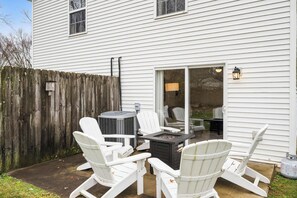 A patio with white Adirondack chairs, a fire pit, and a sliding glass door leading to a covered area. - Entire Duplex, Close to Ark with Private Parking! (Dry Ridge)