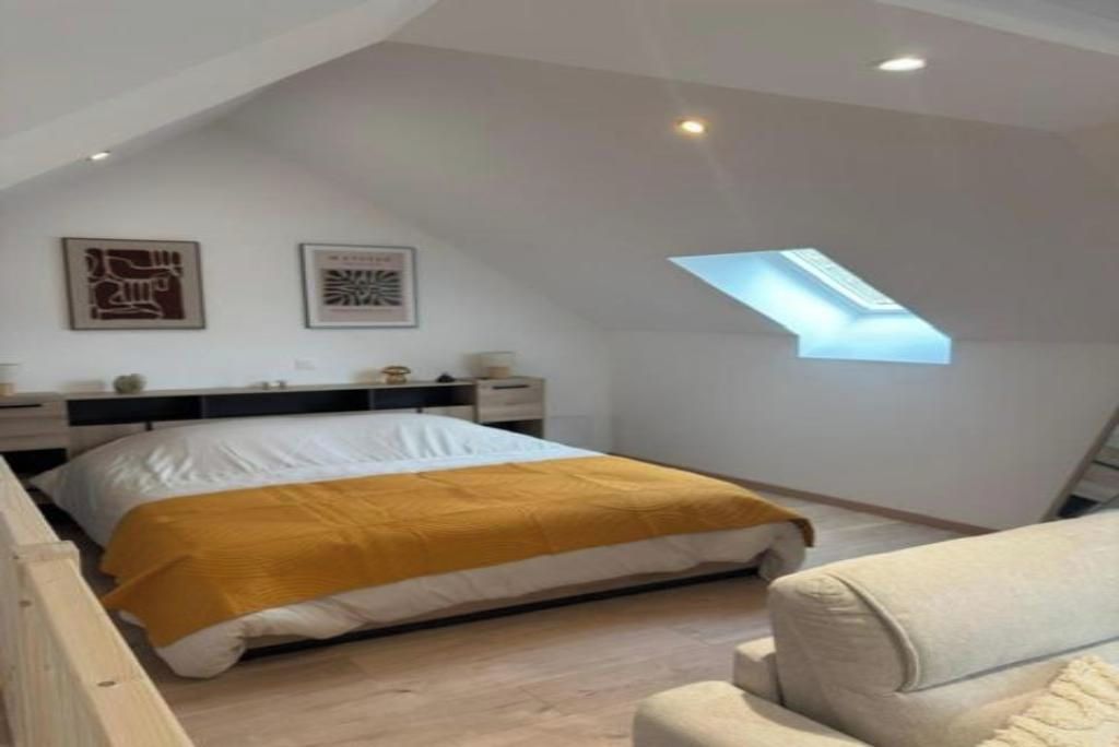Une chambre à coucher comprenant un lit, une table de chevet, une commode, une fenêtre avec vue et un puits de lumière.