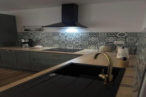 A modern kitchen with a black sink, a coffee maker, and patterned backsplash tiles.
