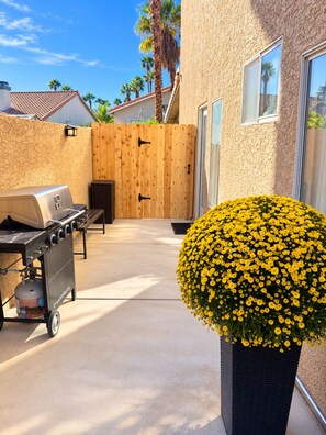 A backyard with a barbecue grill, a wooden fence, and a potted yellow flower. - Villa Tempesto Boutique Residence - Private 2BR Suite and Terrace (Henderson)