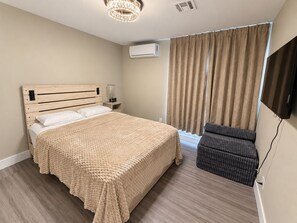 A hotel room with a bed, a TV, a chair, and a window with curtains. - Villa Tempesto Boutique Residence - Private 2BR Suite and Terrace (Henderson)