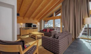 A cozy interior with a wooden ceiling, a sofa set, a dining table, and a kitchen area. - MATTERHORN VIEW RETREAT – ELEGANT 4-BEDROOM ZERMATT APARTMENT (Zermatt)