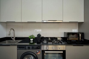 A compact kitchen with a Bosch washing machine, a coffee maker, a microwave, and a sink. - Premium one-bedroom apartment in Fann-Mermoz · Corniche within walking distance (Dakar)