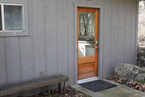 A wooden door with a glass panel, a bench, and a stone wall. - Private! Hidden Gem on the River! (Three Rivers)