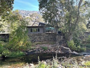 A house with a stone wall and a small pond in front. - Private! Hidden Gem on the River! (Three Rivers)