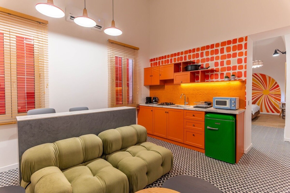 Una cocina moderna con gabinetes naranjas, un lavavajillas verde y un piso estampado.