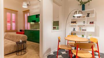 A compact living space with a kitchenette, a dining area with a round table and chairs, and a sofa.
