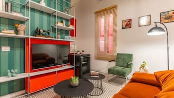 A living room with a red entertainment unit, green armchair, and orange sofa.