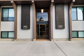 A building facade with the number 140 prominently displayed on two vertical panels, a glass entrance door, and a clear sky visible through the windows. - Downtown 1BR Ideal for Traveling Pros (Twin Falls)