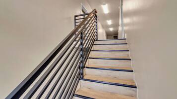 Un escalier avec des marches en bois et une rampe métallique, menant à l’étage supérieur.