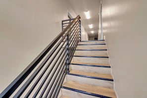 A staircase with wooden steps and a metal handrail, leading to an upper floor. - Downtown 1BR Ideal for Traveling Pros (Twin Falls)