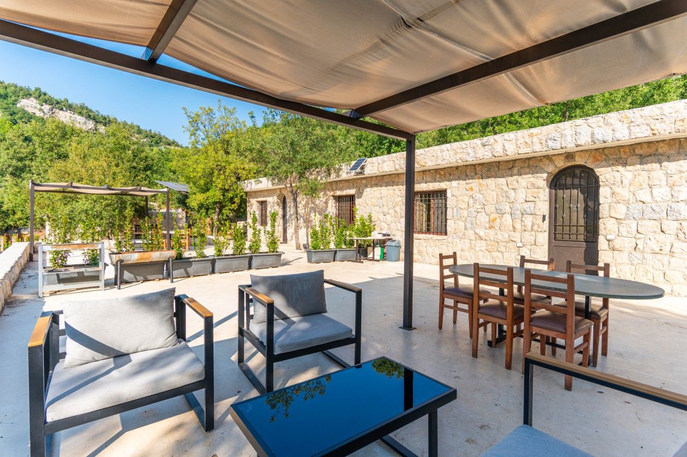 An outdoor patio with seating, a table, and a stone wall backdrop.