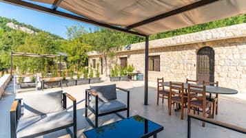 An outdoor patio with seating, a table, and a stone wall backdrop.