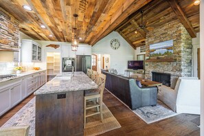 A spacious kitchen with a large island, built-in appliances, and a stone fireplace. - Welcome to Kingfisher- Your Lake James Escape! (Nebo)