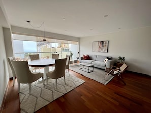 Una sala moderna con comedor, ventanas amplias y vista a la ciudad.