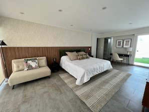 Un dormitorio moderno con cama, sofá, escritorio y vistas al exterior.