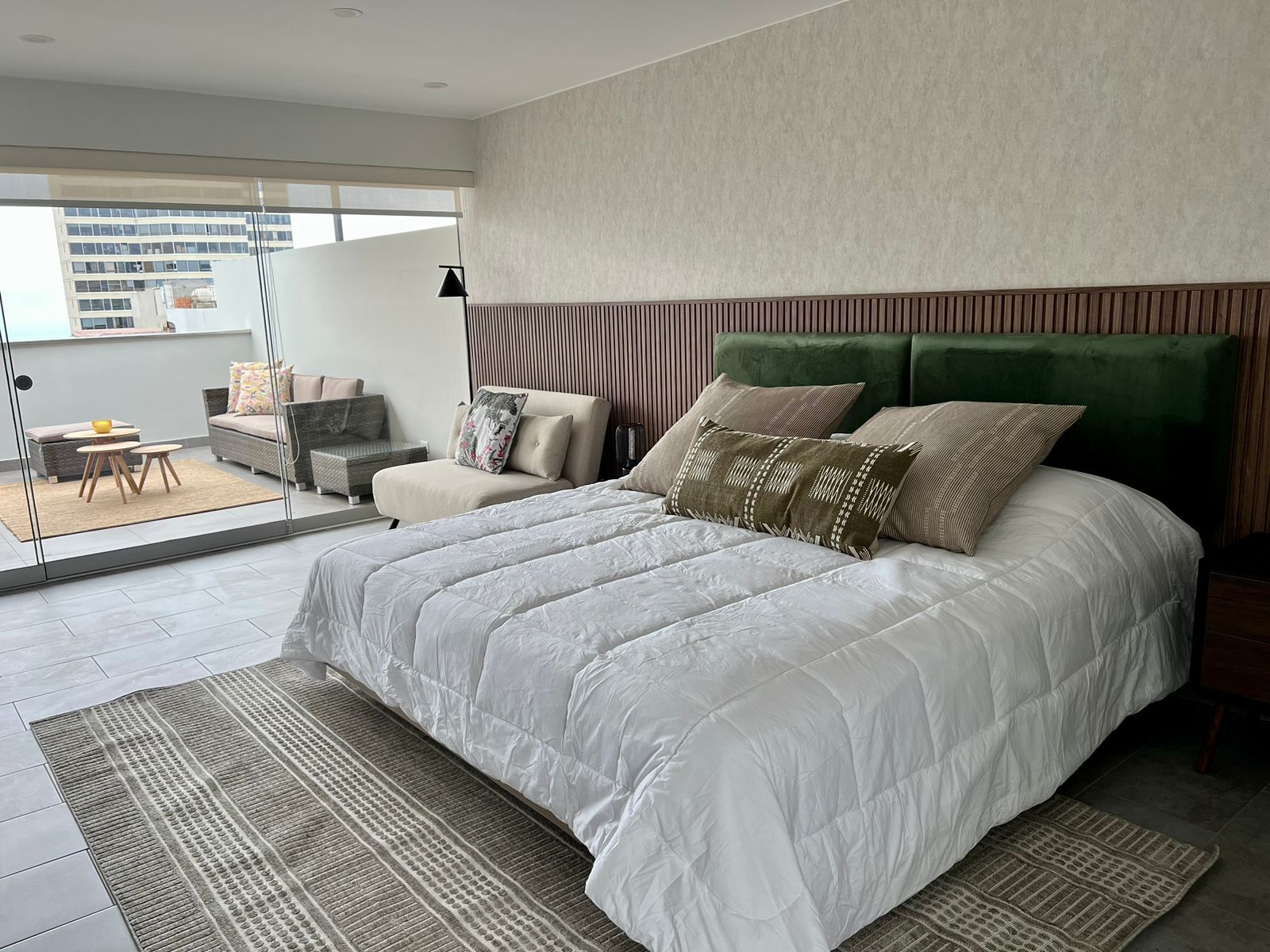 A modern bedroom with a large bed, a sofa, and a dining area with a table and chairs.