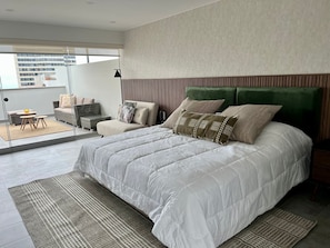 A modern bedroom with a large bed, a sofa, and a dining area with a table and chairs. - Fanning (Miraflores)