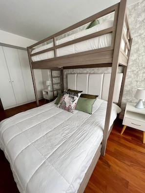 Una litera con colchón blanco, cabecera de madera y dos almohadas.
